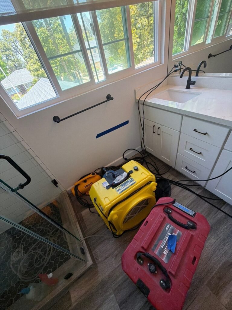 A bathroom with windows, a yellow air mover and a red dehumidifier at work