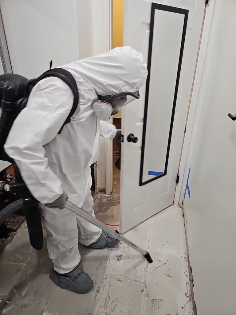 A technician cleaning beside a door over papered floor protection