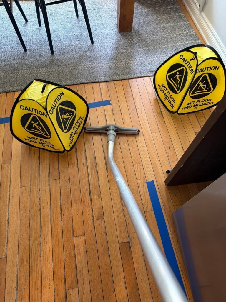 Two yellow wet-floor signs on hardwood with extraction ducting between them